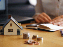 Maison miniature et pièces de monnaies posées sur un bureau (c) Freepik
