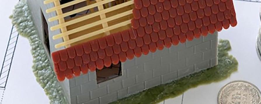 Maquette de maison en cours de construction, sur des plans d'architecte