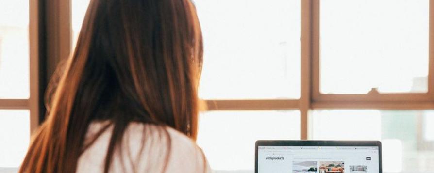 Deux femmes de dos assises consultant un ordinateur